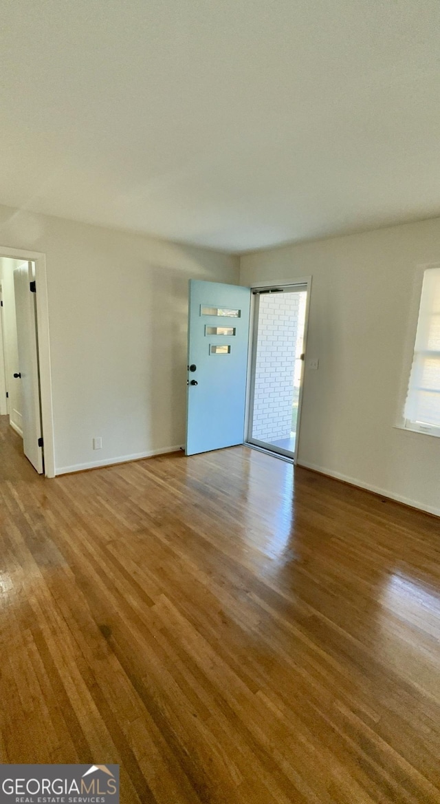 unfurnished living room with wood finished floors and baseboards