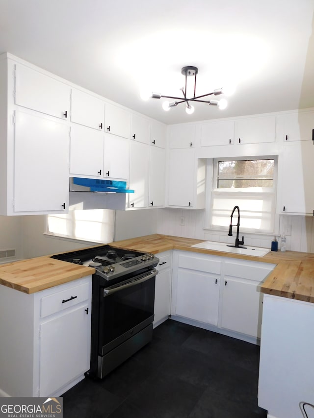 kitchen with decorative backsplash, butcher block counters, under cabinet range hood, a sink, and gas stove