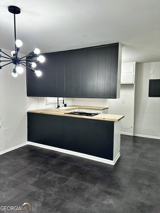 kitchen with pendant lighting, a chandelier, wood counters, gas cooktop, and dark cabinets