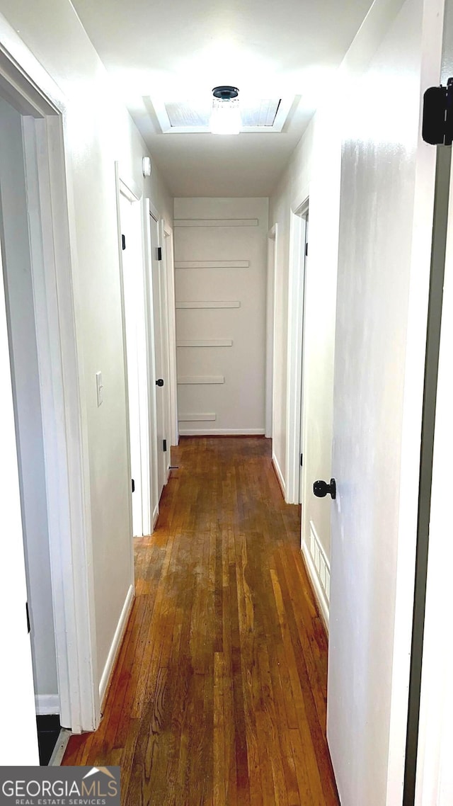 hallway featuring visible vents, hardwood / wood-style flooring, and baseboards