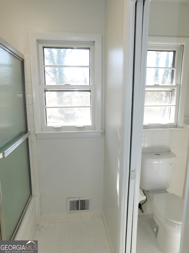 bathroom with toilet, plenty of natural light, tile patterned flooring, and visible vents