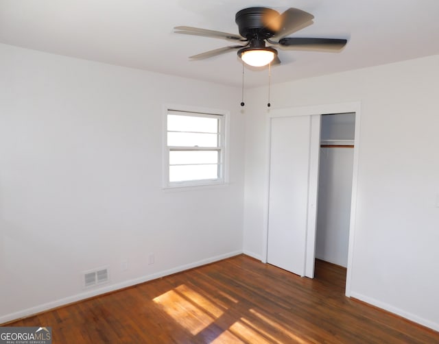 unfurnished bedroom with a closet, wood finished floors, visible vents, and baseboards