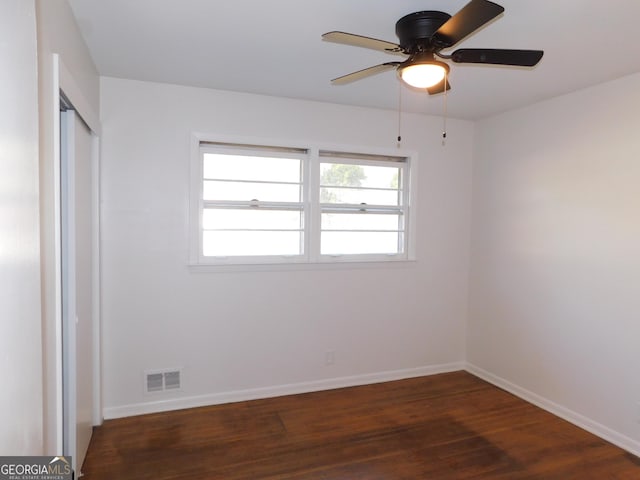 unfurnished room featuring dark wood-type flooring, plenty of natural light, visible vents, and baseboards