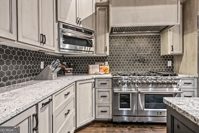 kitchen featuring premium range hood, decorative backsplash, double oven range, and light stone counters