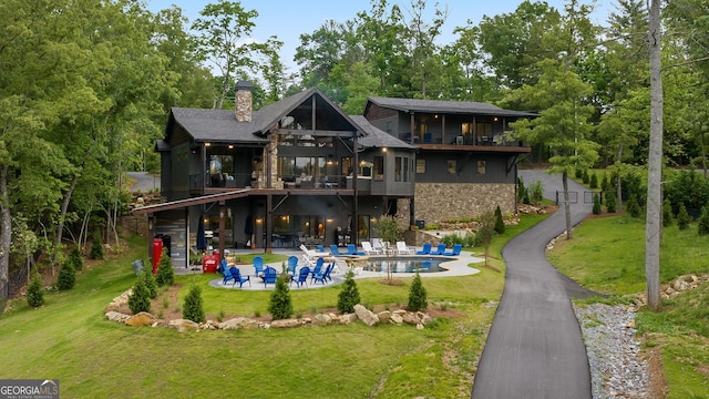 back of property with a lawn, a balcony, and a patio