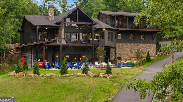 rear view of house with a lawn, a patio area, and a balcony