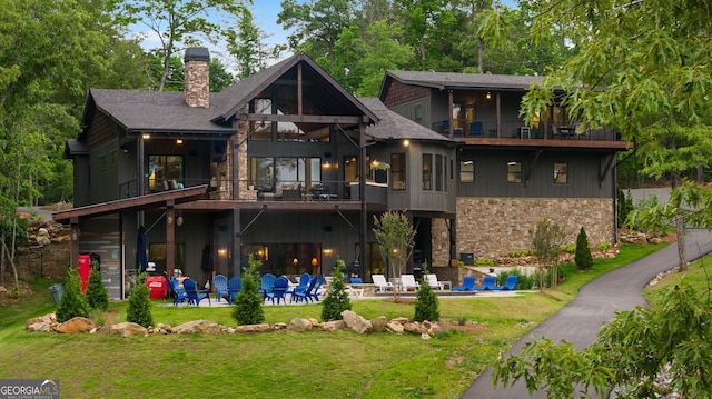 rear view of house featuring a lawn, a patio area, and a balcony