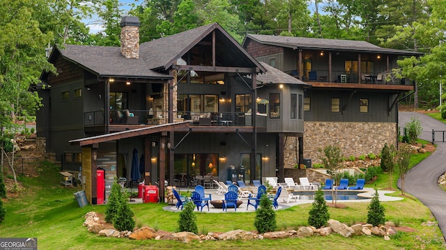 back of property with a yard, a balcony, and a patio area