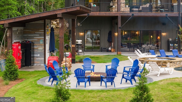 exterior space with a lawn, a patio area, a balcony, and an outdoor fire pit