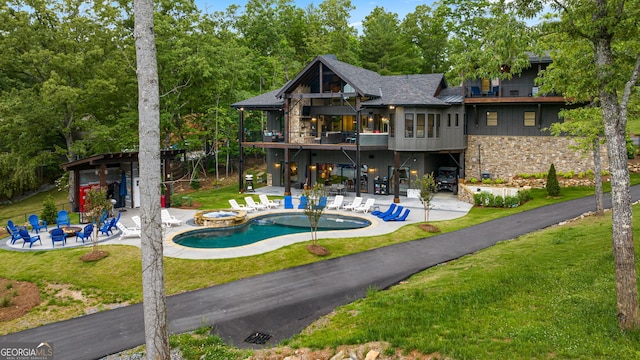 rear view of property featuring a fire pit, a balcony, a patio, and a lawn