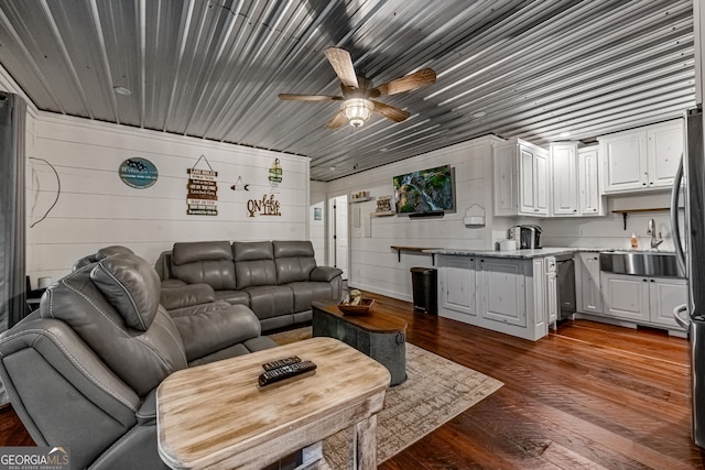 living room featuring wooden walls, sink, ceiling fan, and dark hardwood / wood-style floors