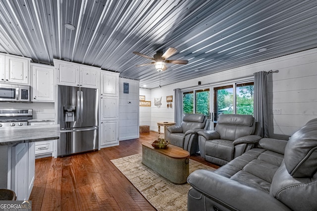 cinema room with wood walls, dark hardwood / wood-style floors, and ceiling fan