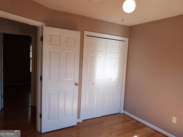 unfurnished bedroom featuring wood-type flooring, a closet, and a textured ceiling