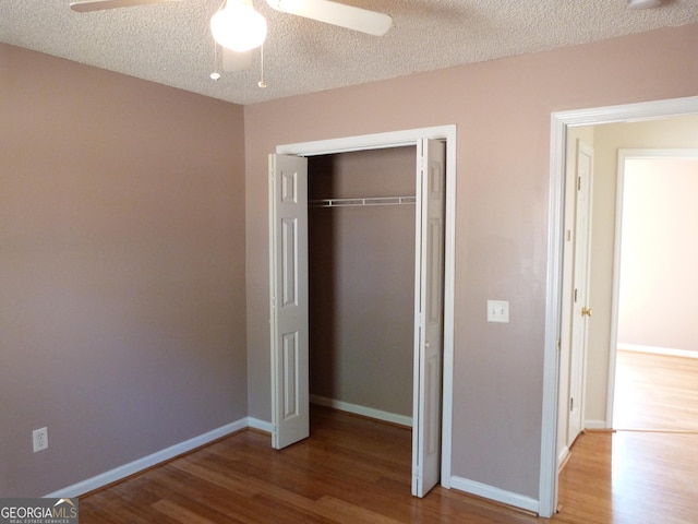 unfurnished bedroom featuring ceiling fan, hardwood / wood-style floors, a textured ceiling, and a closet