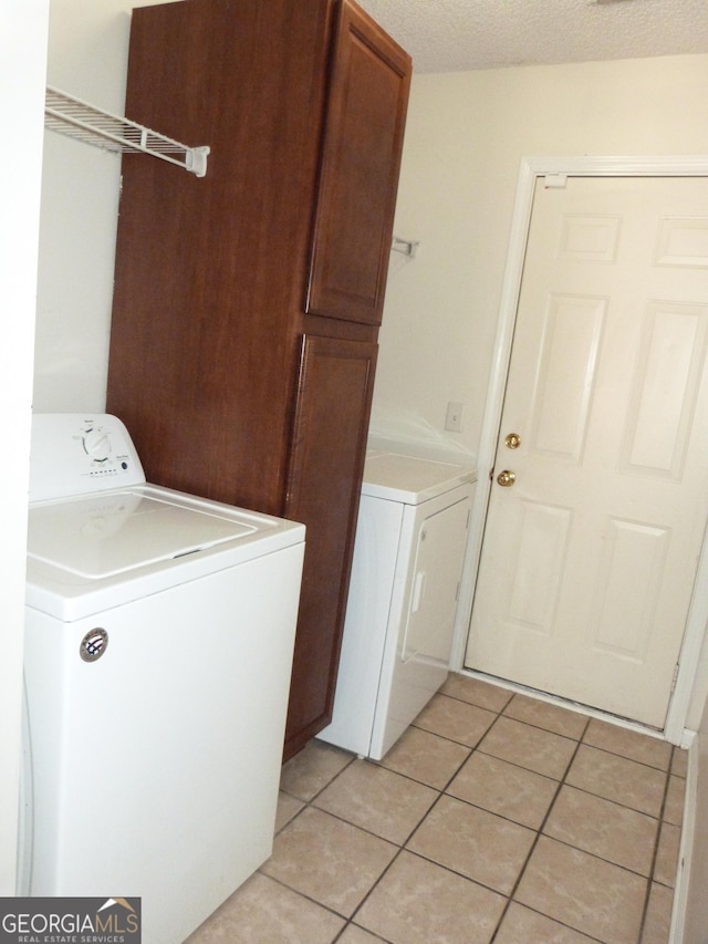 laundry room with cabinets, washer / dryer, a textured ceiling, and light tile patterned floors