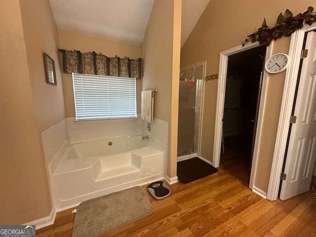 bathroom with wood-type flooring, shower with separate bathtub, and vaulted ceiling