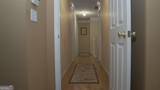 hallway with light hardwood / wood-style flooring and ornamental molding