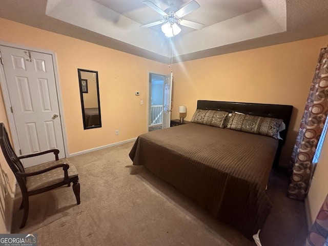 carpeted bedroom featuring ceiling fan, a closet, and a tray ceiling