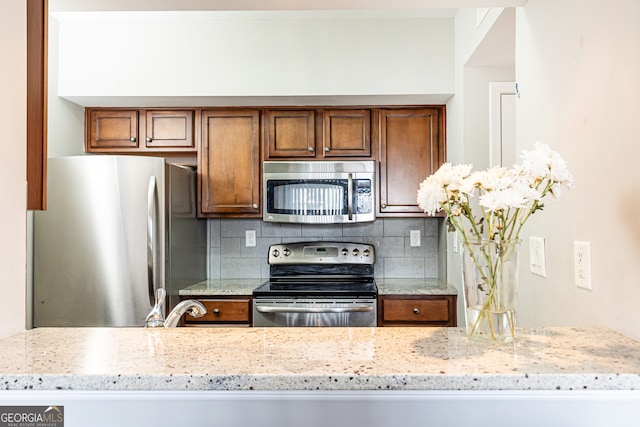 kitchen with sink, light stone countertops, backsplash, and appliances with stainless steel finishes