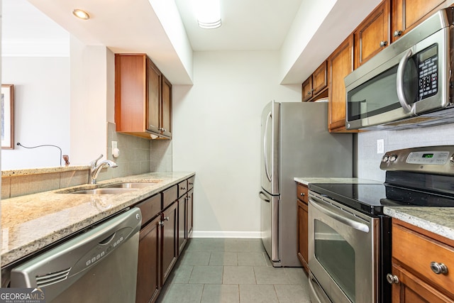 kitchen featuring light stone counters, sink, decorative backsplash, and stainless steel appliances