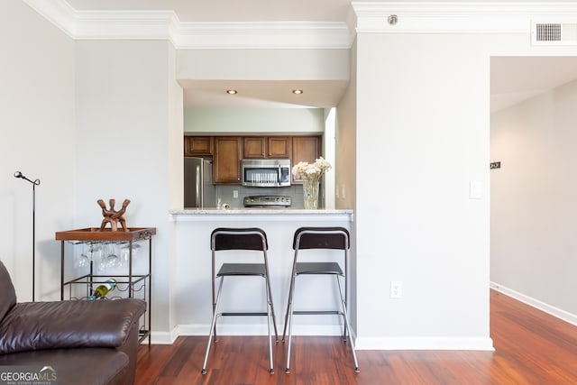 kitchen with light stone countertops, stainless steel appliances, kitchen peninsula, a breakfast bar area, and decorative backsplash