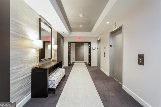 hall with elevator and a tray ceiling