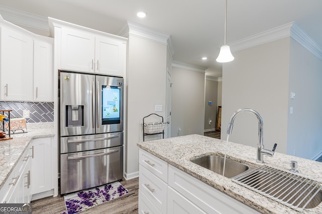 kitchen with white cabinets, stainless steel fridge, decorative backsplash, and light stone countertops