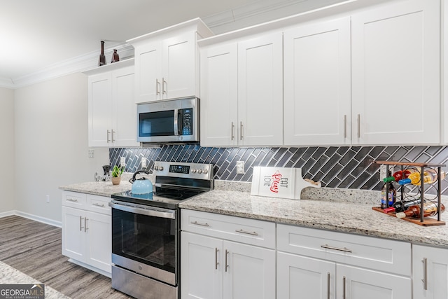 kitchen with appliances with stainless steel finishes, backsplash, crown molding, light hardwood / wood-style flooring, and white cabinetry