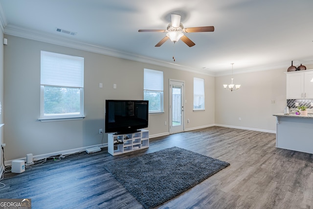 living room with ceiling fan with notable chandelier, a healthy amount of sunlight, and ornamental molding