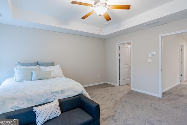 bedroom featuring light carpet, a raised ceiling, and ceiling fan