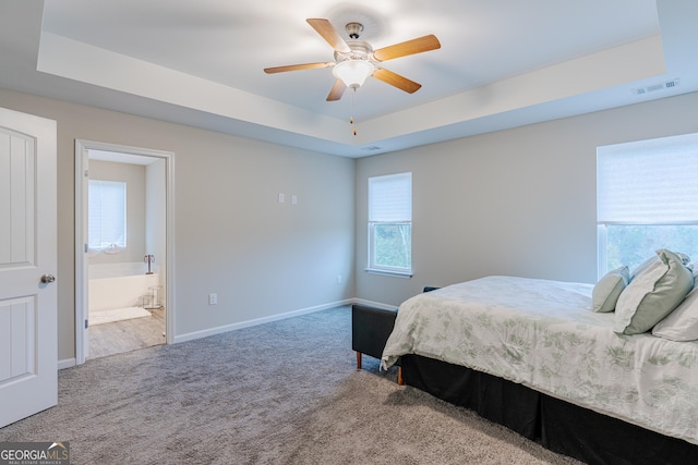 bedroom featuring carpet floors, ensuite bath, a raised ceiling, and ceiling fan