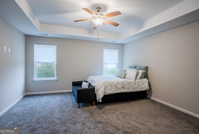 carpeted bedroom featuring a raised ceiling and ceiling fan