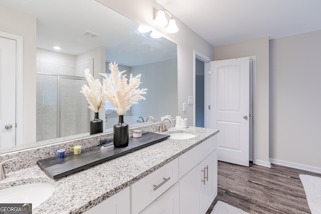 bathroom featuring hardwood / wood-style floors, vanity, and a shower with shower door