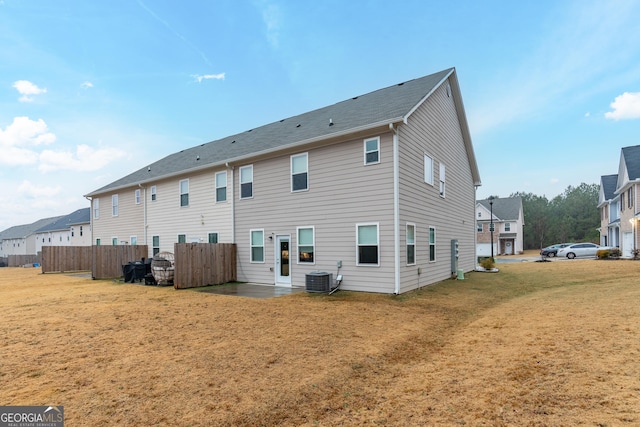 rear view of property with central AC unit and a yard