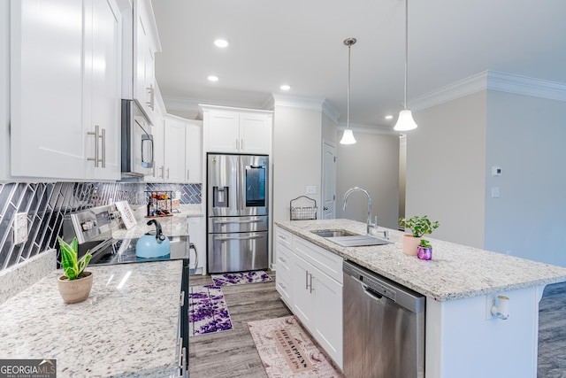 kitchen with appliances with stainless steel finishes, sink, pendant lighting, white cabinetry, and an island with sink