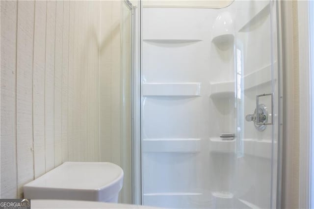 bathroom with wooden walls and a shower with door