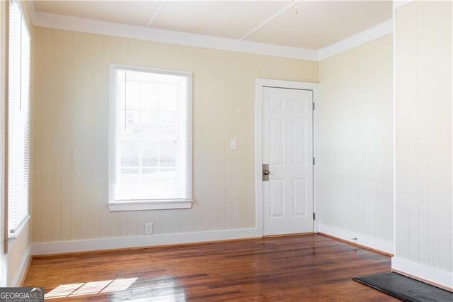 empty room with plenty of natural light, ornamental molding, and wood-type flooring