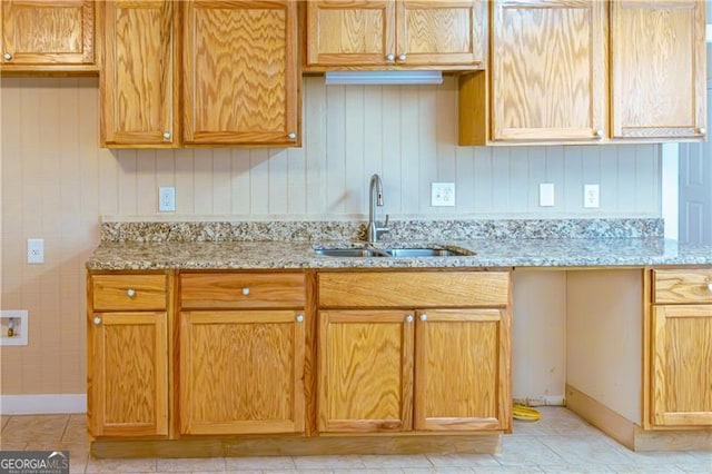 kitchen with light stone counters, sink, and light tile patterned floors