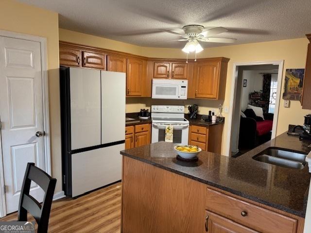 kitchen with white appliances, sink, ceiling fan, a textured ceiling, and kitchen peninsula