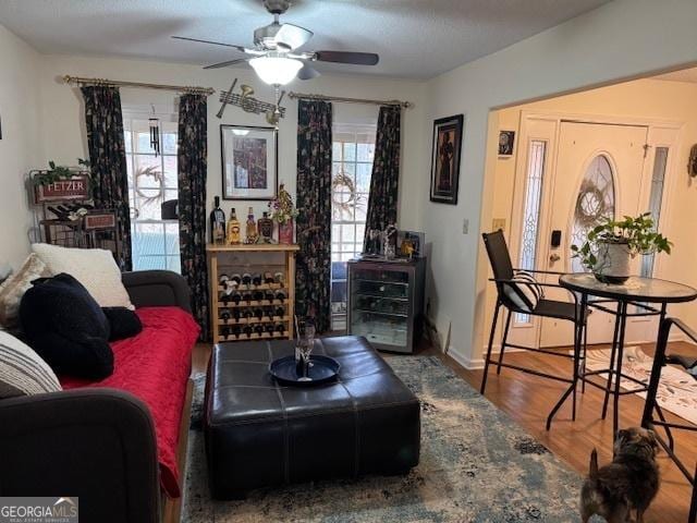 living room with ceiling fan, wood-type flooring, and a textured ceiling