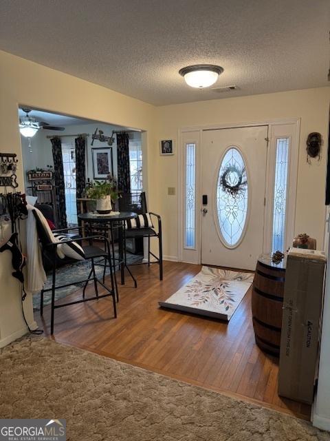 entryway featuring ceiling fan, wood-type flooring, and a textured ceiling