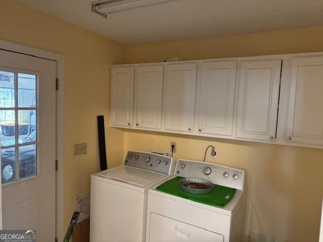 clothes washing area featuring washing machine and dryer and cabinets