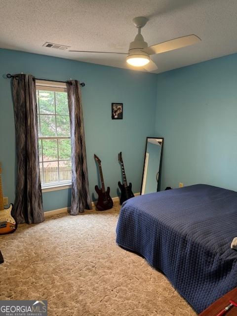 carpeted bedroom featuring ceiling fan and a textured ceiling