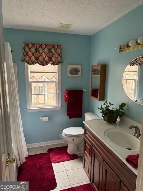 bathroom featuring tile patterned floors, vanity, a textured ceiling, and toilet