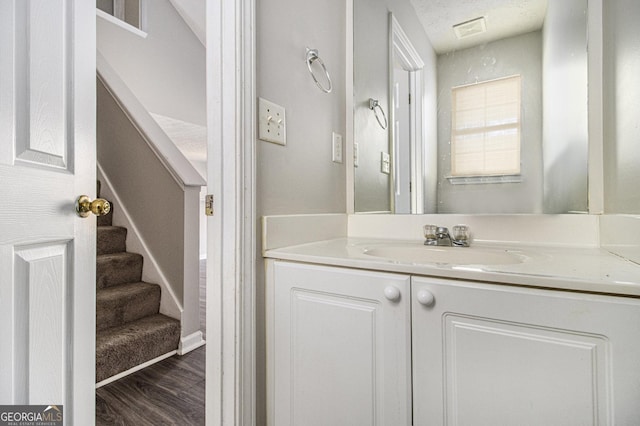 bathroom with hardwood / wood-style floors, vanity, and a textured ceiling