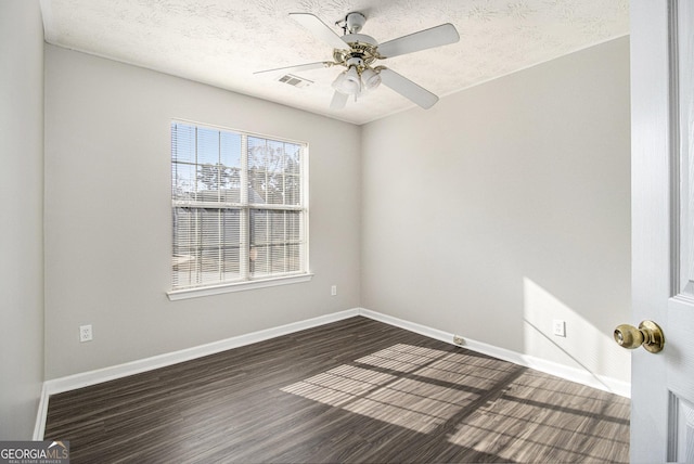 empty room with ceiling fan, dark wood-type flooring, and a textured ceiling