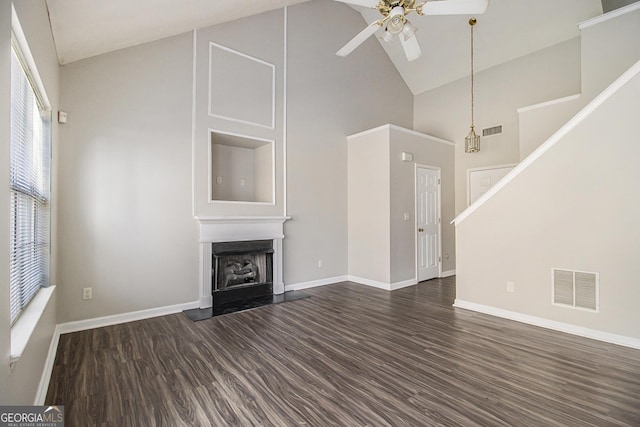 unfurnished living room with ceiling fan with notable chandelier, dark hardwood / wood-style floors, and high vaulted ceiling