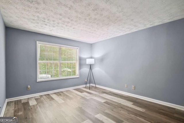 unfurnished room featuring wood-type flooring and a textured ceiling