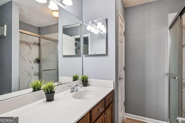 bathroom with a textured ceiling, vanity, and an enclosed shower