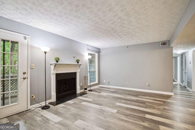 unfurnished living room featuring hardwood / wood-style flooring and a textured ceiling